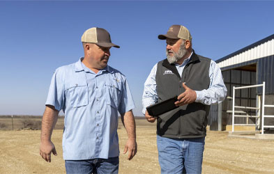 Dairy Farmers of America employee holding a tablet and walking next to a farmer