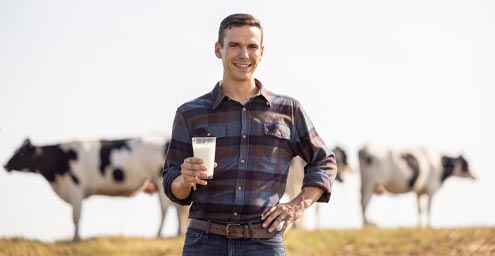 Man holding glass of milk in a field